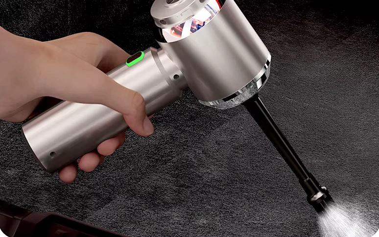 A hand holding the Veylans V1 as its blower nozzle drives dust out of a car carpet